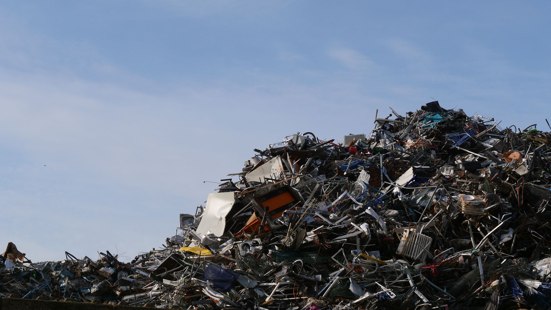 A vast pile of metal scrap and debris under a clear sky, captured at a junkyard
